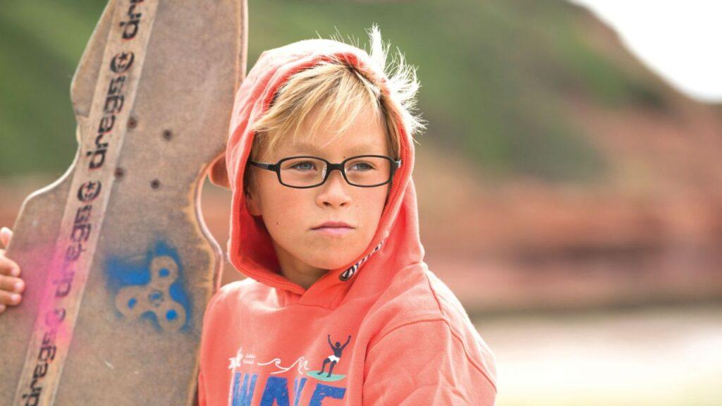 Child holding a surfboard with glasses on. EK Eyewear Belfast.